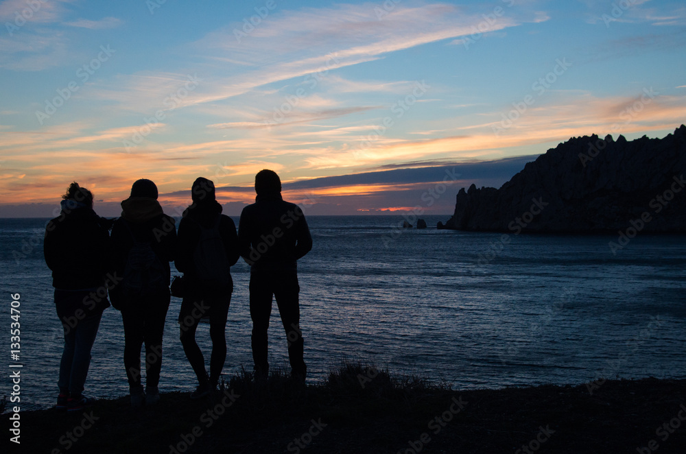 four friends watching the sunset on the sea