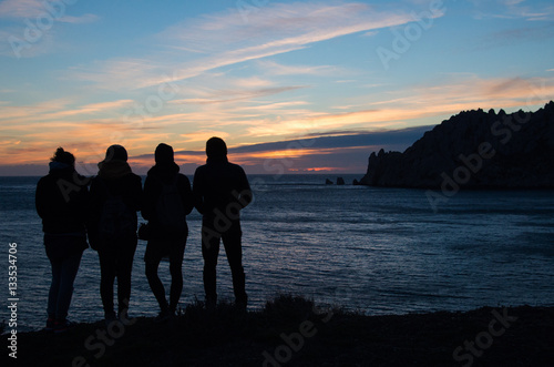 four friends watching the sunset on the sea