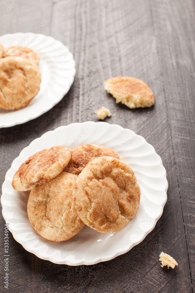 Two plates of Crumbled Snickerdoodle Cookies on a dark wooden background angled shot Two plates of Crumbled Snickerdoodle Cookies on a dark wooden background angled shot
