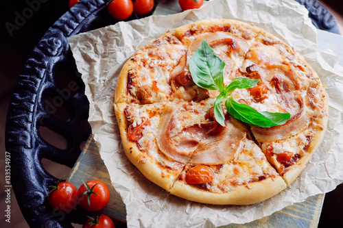 Tasty pizza with becon topped leaf of basil photo