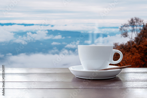 Morning coffee cup on beautiful landscape of mist and mountain