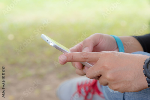 Man hands holding using mobile phone on green nature background