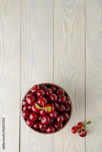 Fototapeta Naklejka Na Ścianę i Meble -  ripe cherries in a bowl on a textured wooden background, view from above