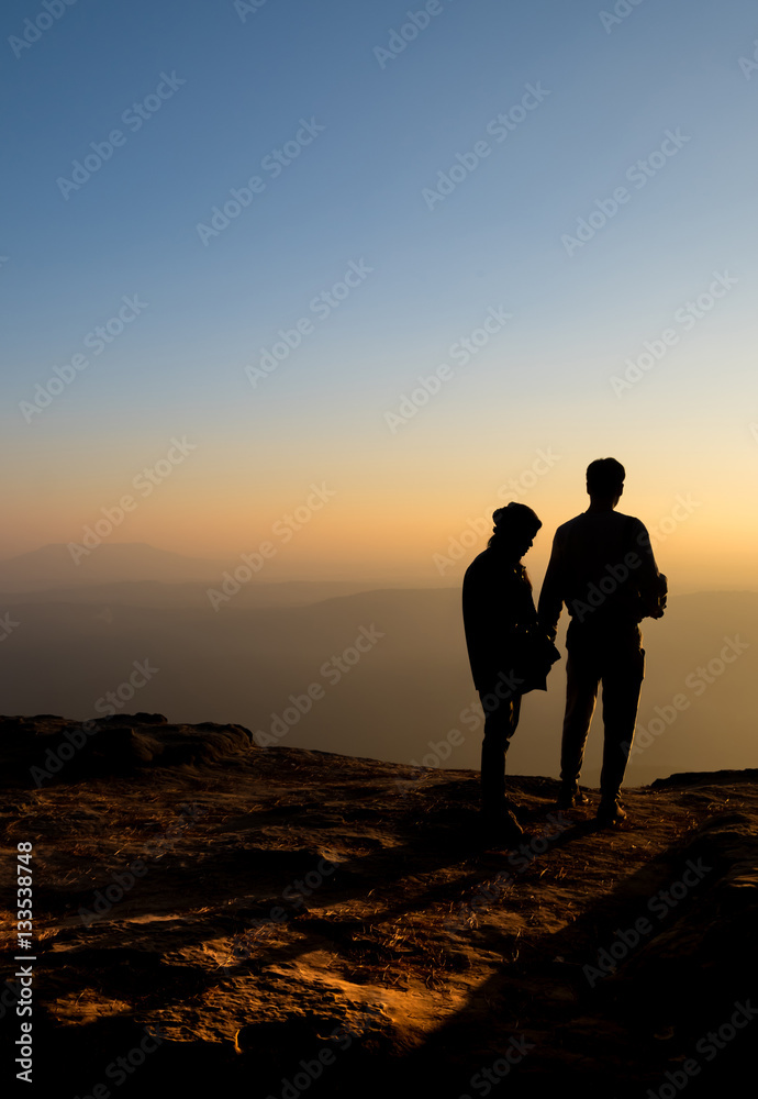 Silhouette of lovers waiting for sunrise sunset on mountain whil