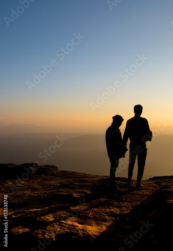 Silhouette of lovers waiting for sunrise sunset on mountain whil