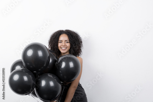 Portrait of a brunette woman having fun with black balloons