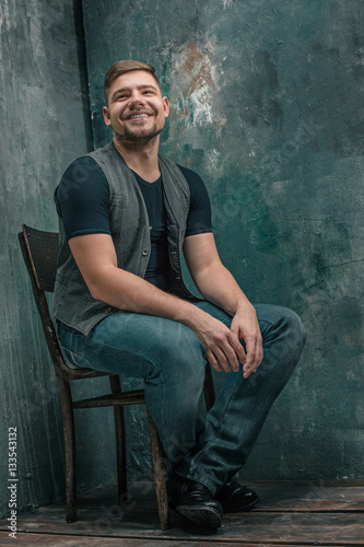 Portrait of smiling happy man sitting on the chair in studio