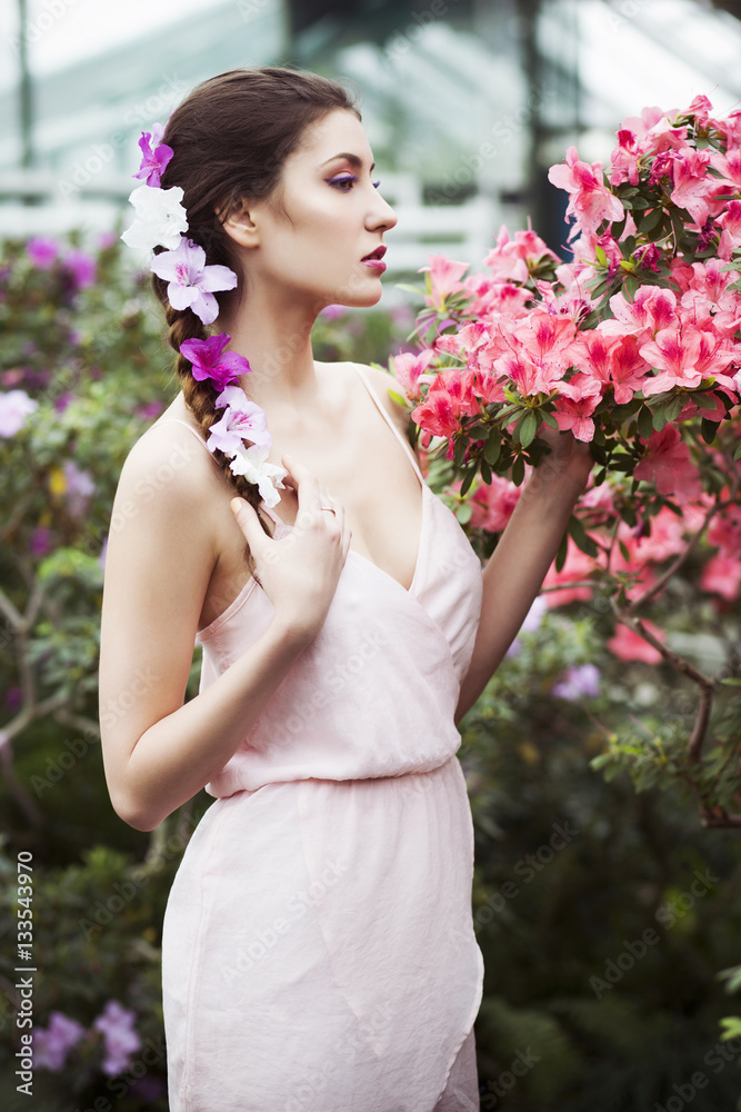 Beautiful brunette woman in flower garden with red pink azalea in a sensual dress Beautiful brunette woman in flower garden with red pink azalea in a sensual dress