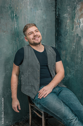 Portrait of smiling happy man sitting on the chair in studio