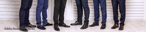 Six men's feet in black leather shoes