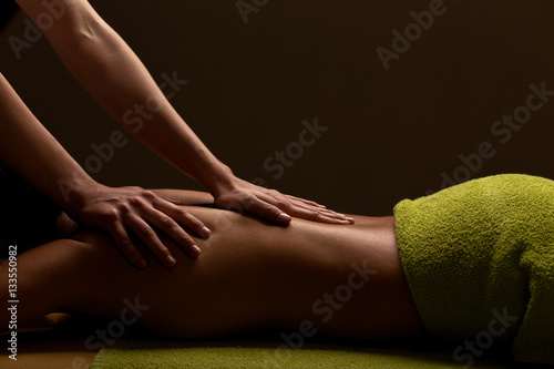 close-up masseur hands doing back massage in spa center. low key