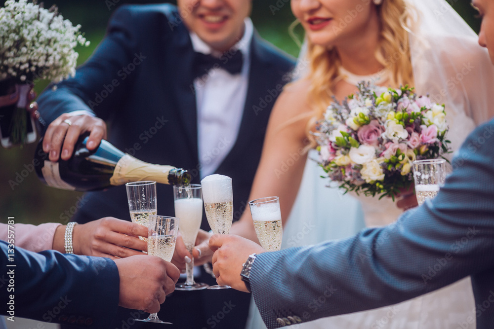 Bride and groom with happy groomsmen and bridesmaids having fun and popping champagne, luxury wedding celebration, hilarious moment. Newlyweds fun with friends.