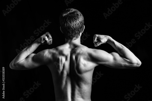 Portrait of young and fit teen model posing his muscles in studio © rimmdream