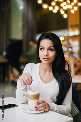 Young woman at cafe drinking coffee
