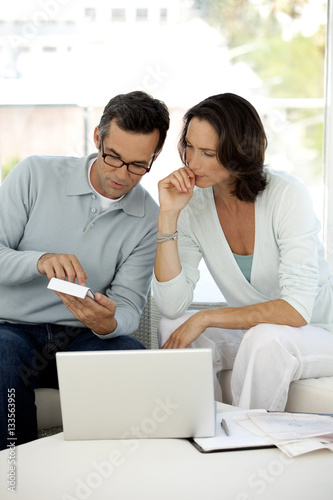 Mature Caucasian couple doing home finances on sofa