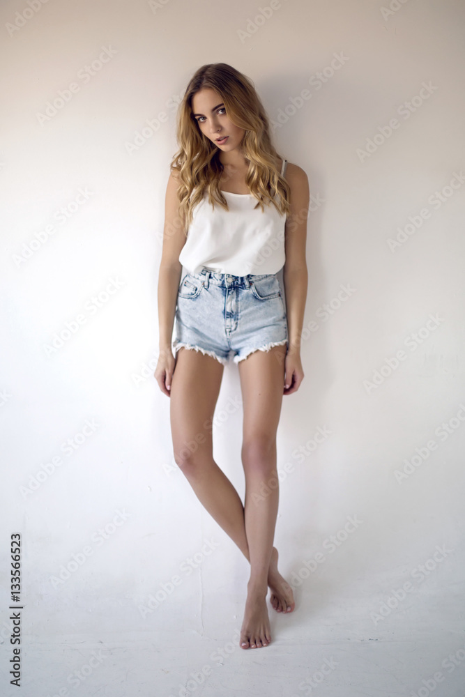 young sexy blonde girl in short denim shorts and a white t-shirt on white  background Stock Photo | Adobe Stock