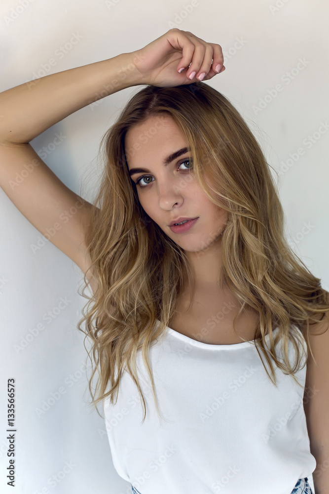 young sexy blonde girl in short denim shorts and a white t-shirt on white background young sexy blonde girl in short denim shorts and a white t-shirt on white background
