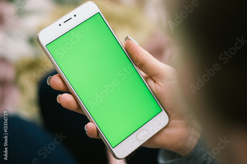 Valokuva Beautiful girl holding a smartphone in the hands of a green screen green screen,