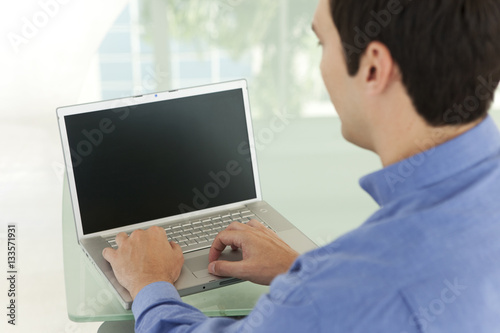 Single Caucasian businessman using laptop in office