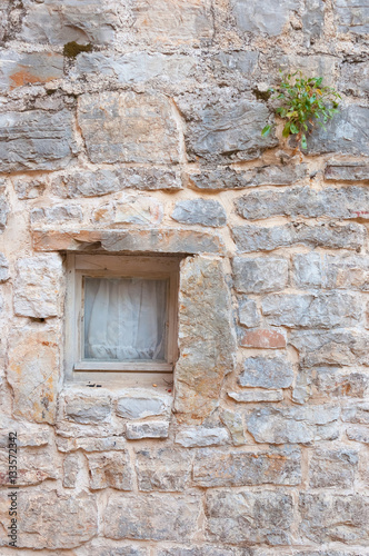 Small window at stone wall in Old Town of Budva, Montenegro.