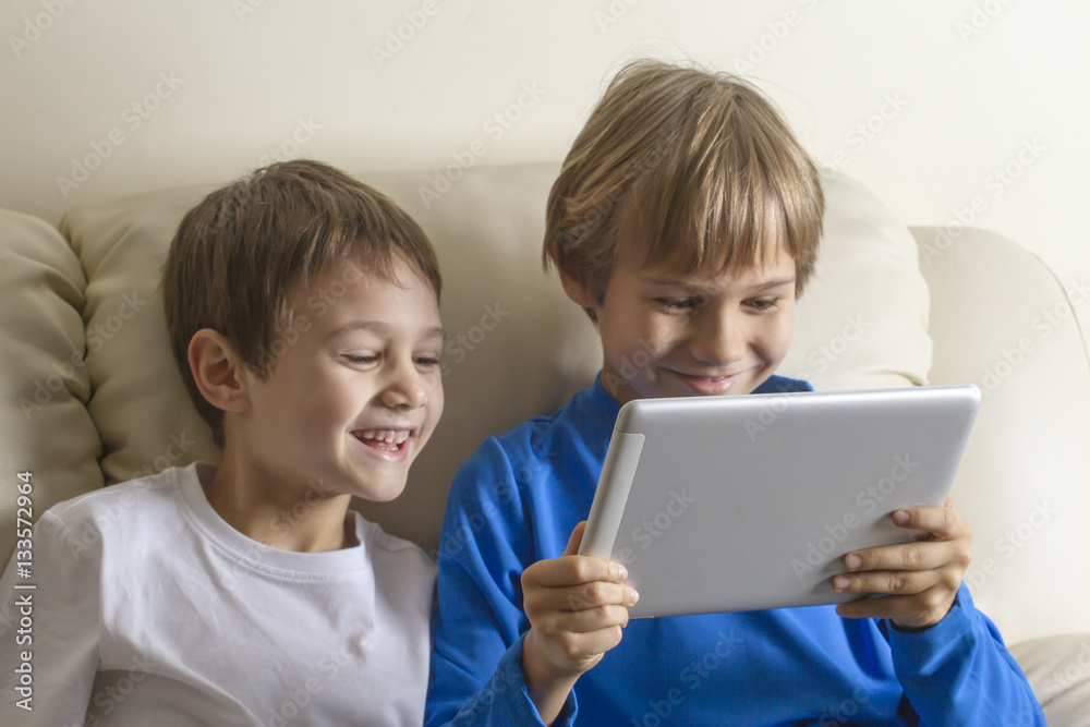 Children with tablet PC. Boys looking at screen, smiling and playing games or watching video. People education learning technology leisure concept Children with tablet PC. Boys looking at screen, smiling and playing games or watching video. People education learning technology leisure concept