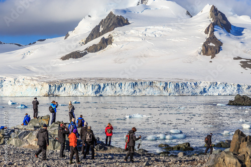 Group of tourists looking at the glacier at the stony shore of H