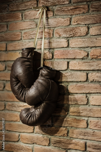 Pair of brown retro boxing gloves hanging on wall © romanets_v