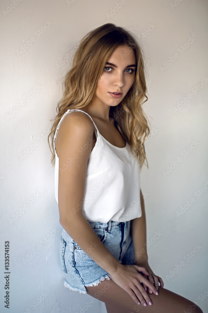 young sexy blonde girl in short denim shorts and a white t-shirt on white  background Stock Photo | Adobe Stock