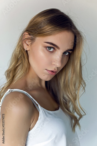 young sexy blonde girl in short denim shorts and a white t-shirt on white background