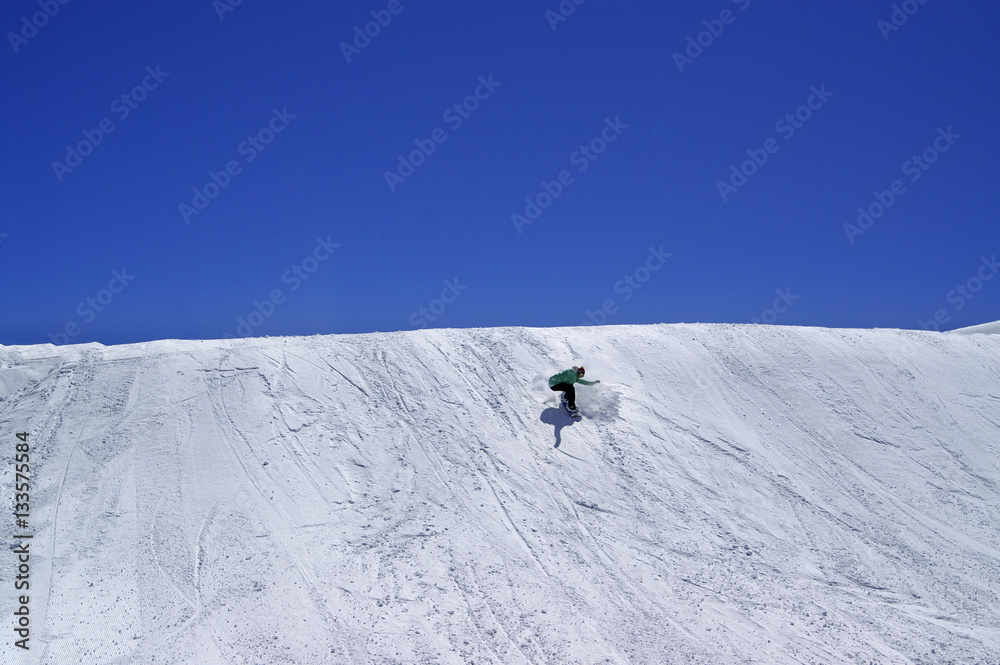 Snowboarder in terrain park and blue clear sky at ski resort