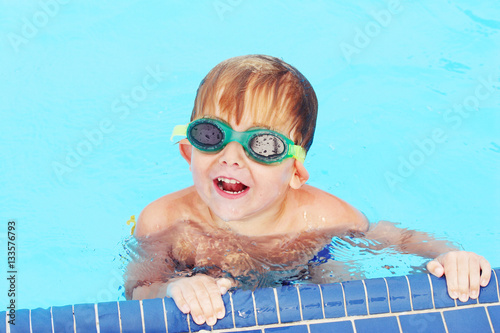 Smiling preschool boy wearing googles in pool