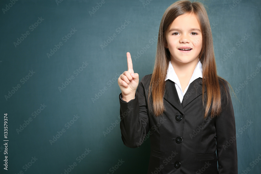 Cute little girl standing on green blackboard background