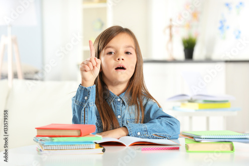 Little girl with books sitting at table