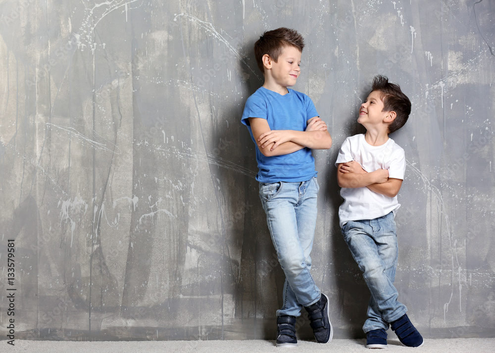 Cute little brothers standing on grey textured background