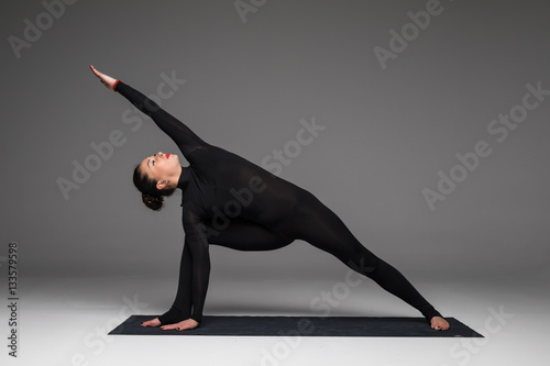 Utthita parsvakonasana. Beautiful yoga woman practice yoga poses on grey background. Yoga concept. photo