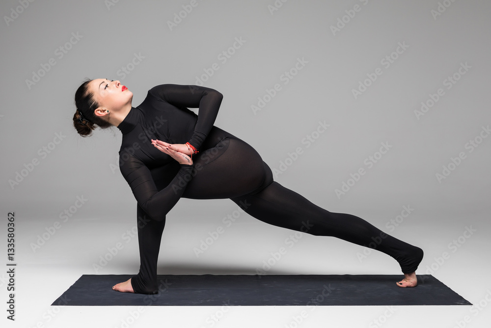 Obraz premium Utthita parsvakonasana. Beautiful yoga woman practice yoga poses on grey background. Yoga concept.