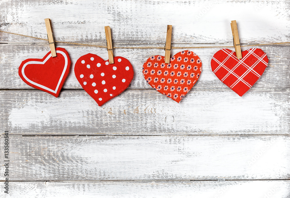 Fototapeta premium handmade toy hearts hanging from a rope on a white wooden background. Valentine 