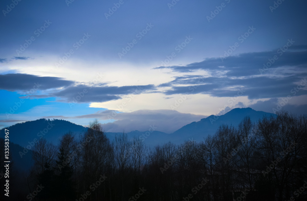 Silhouettes of trees and mountains against the winter sky