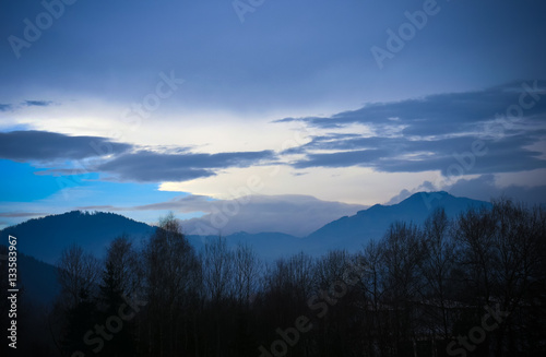Silhouettes of trees and mountains against the winter sky