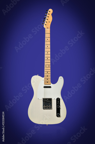 Beige six-string electric guitar standing vertically isolated on a blue background