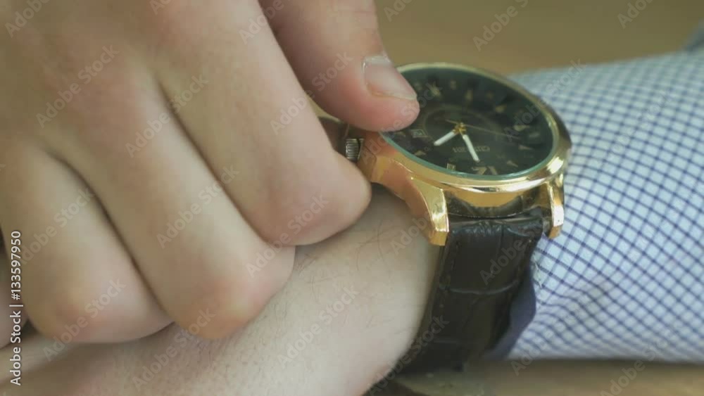 The man checks the time of the wristwatch. Close up