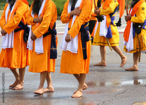 men of Sikh Religion with long orange clothes walk barefoot