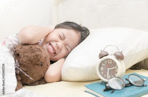 Quadro su tela Annoyed girl being awakened by an alarm clock