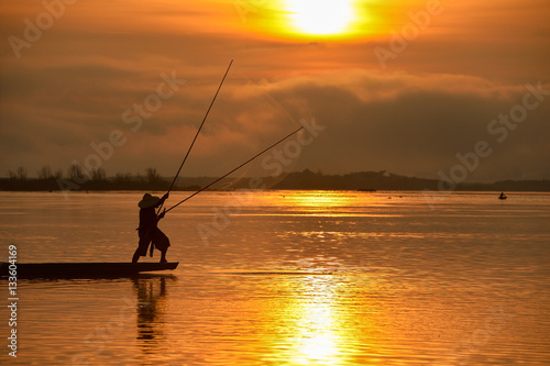 The silluate fisherman boat in river on during sunrise,Thailand