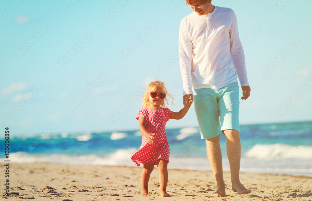 father and cute little daughter walk at beach