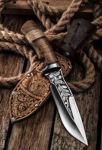 Hunting Knife with leather sheath on a wooden table