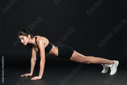 Concentrated beautiful fitness girl in sportwear exercising doing plank