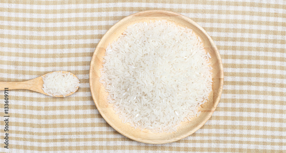 Uncooked white rice on wooden plate and spoon on top view 2 Uncooked white rice on wooden plate and spoon on top view 2