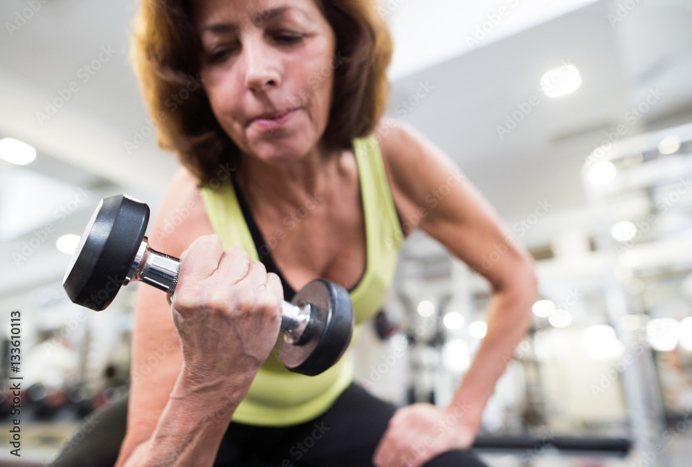 Senior woman in gym working out with weights. Senior woman in gym working out with weights.
