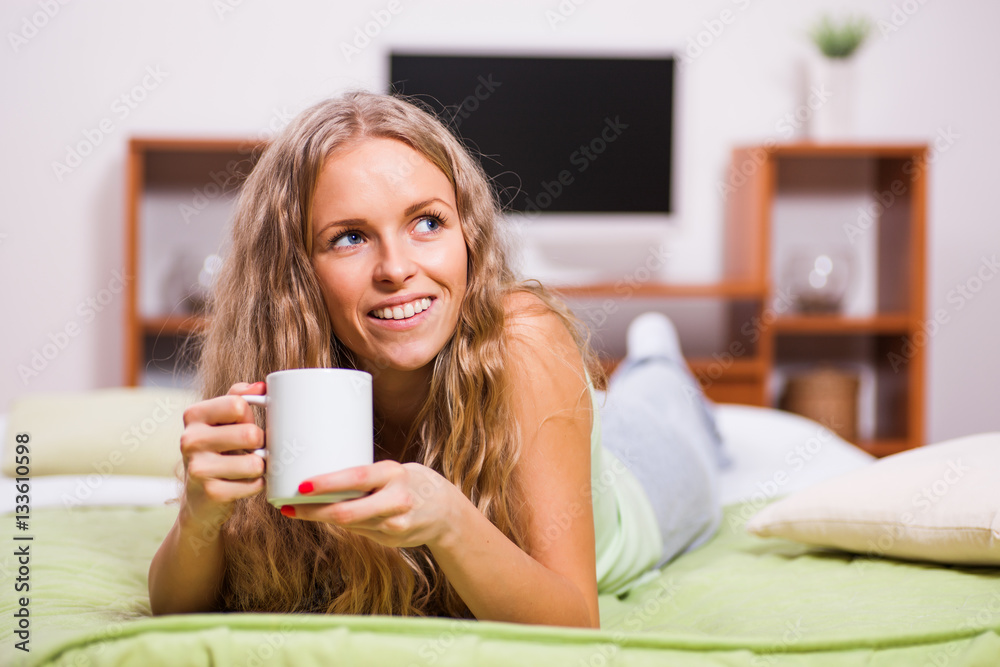 Young woman is lying in bed and drinking tea. Young woman is lying in bed and drinking tea.